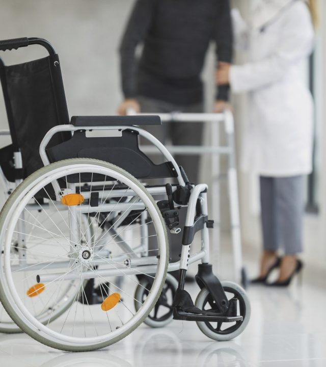 Close up of wheelchair with blur view of patient and doctor in the background, free public domain CC0 photo.